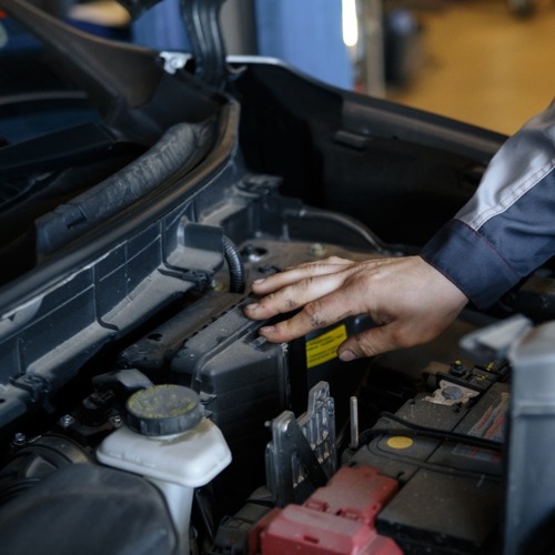 A Mechanic Looks Under a Car's Hood.